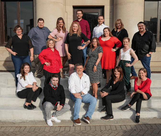 The Red Caffeine team sitting on the steps of their office, everyone smiling