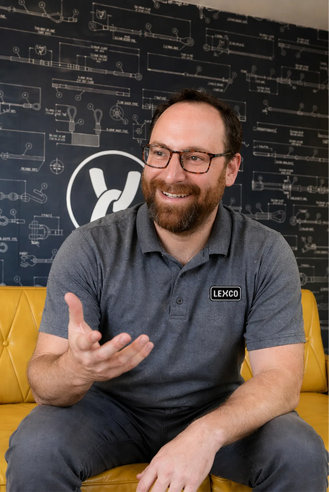 Man-in-glasses-sitting-on-sofa-in-gray-shirt-smiling