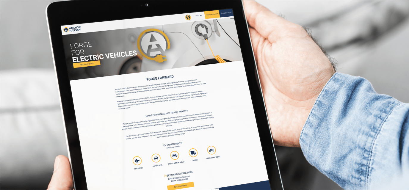 Hands holding a tablet that shows the Anchor Harvey Electric Vehicle website