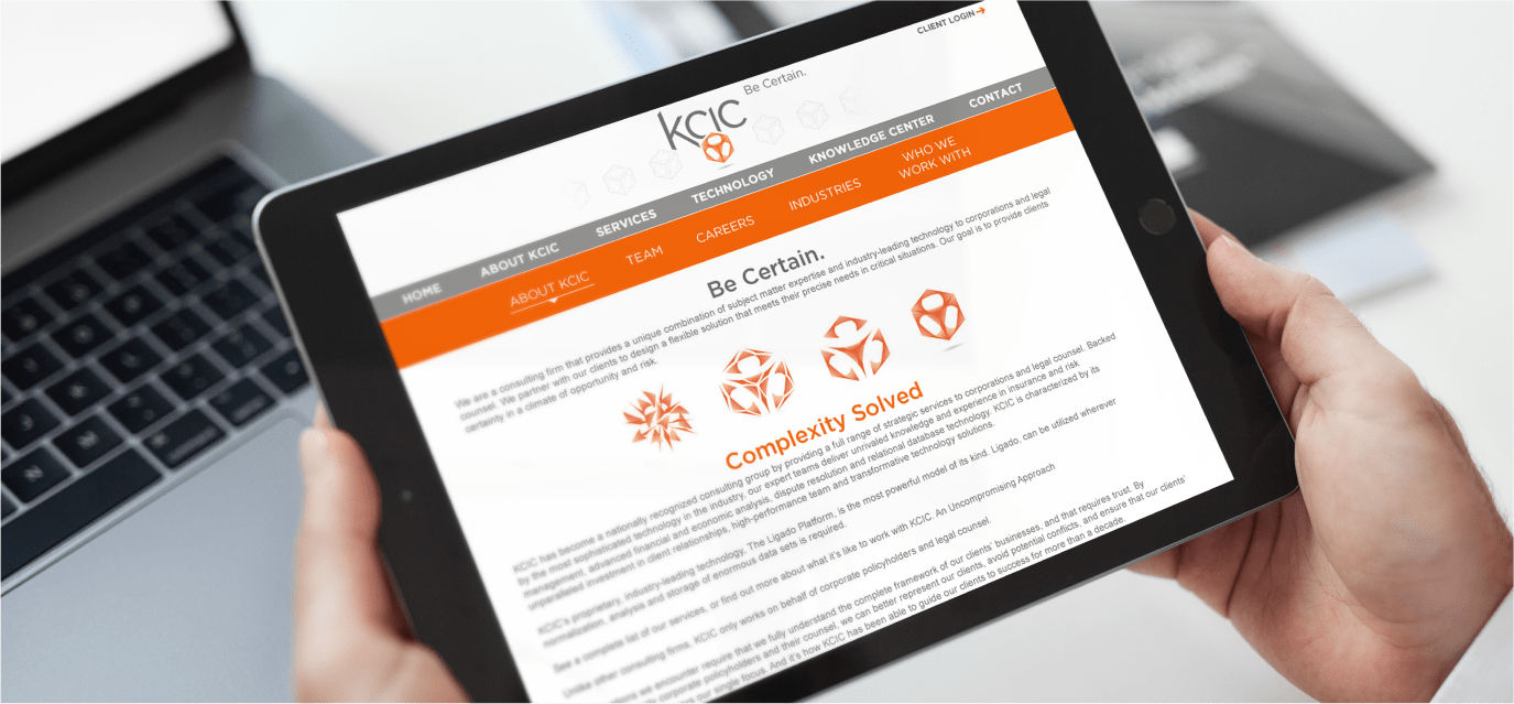 Hands holding a tablet that displays the KCIC website