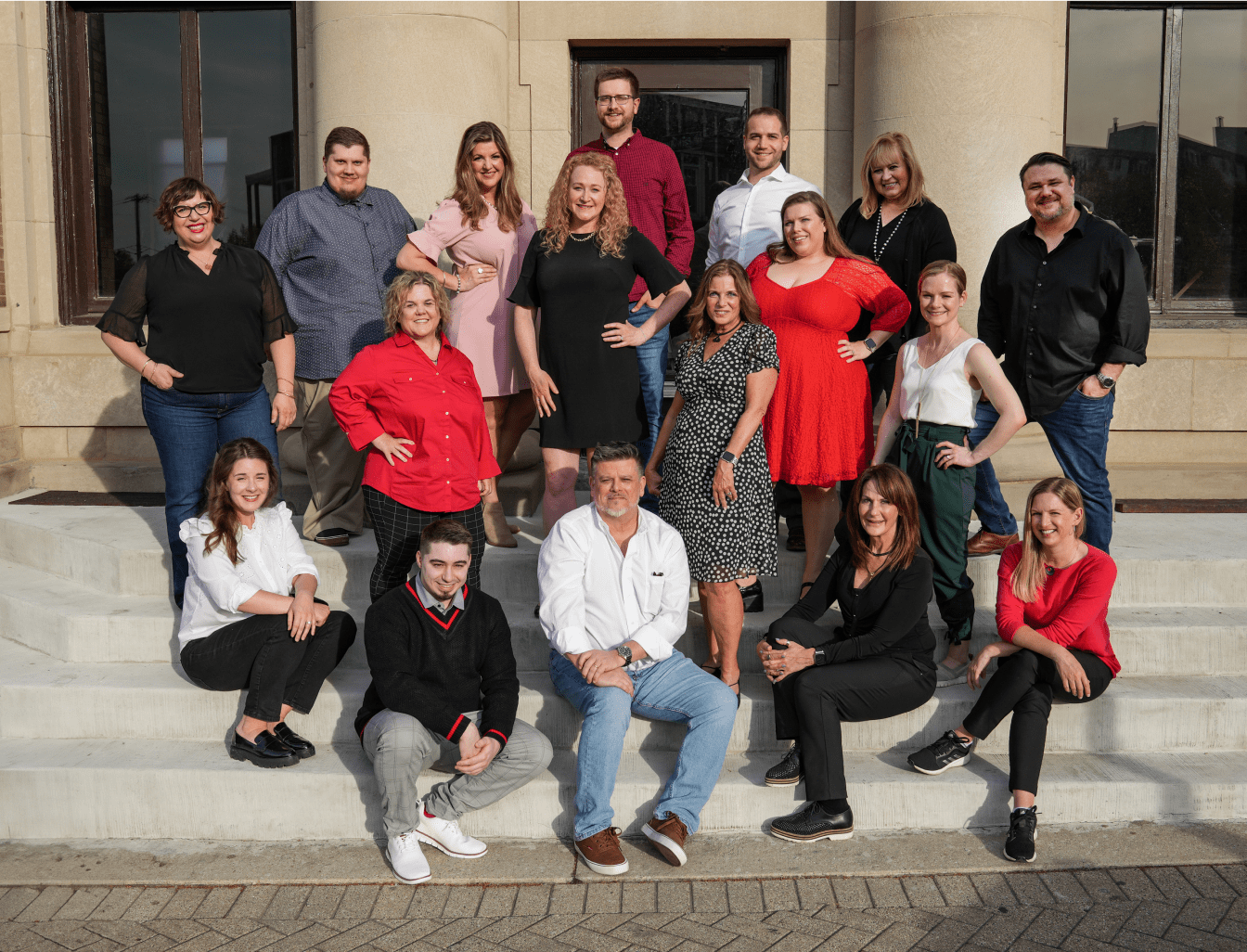 The Red Caffeine team sitting on the steps of their office, everyone smiling